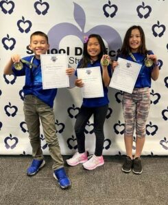 3 students holding their certificates from Battle of the Books battle