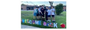 Kids standing in front of Welcome Back sign