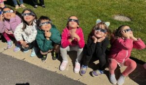 Students sitting with solar eclipse glasses on