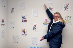 Alex standing by students' pictures